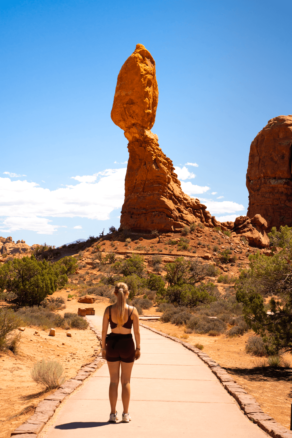 Balanced Rock in Arches National Park, Utah, with a woman standing in the foreground