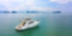 A white yacht on calm ocean water under a partly cloudy sky, with distant islands visible on the horizon. Serene and peaceful setting.
