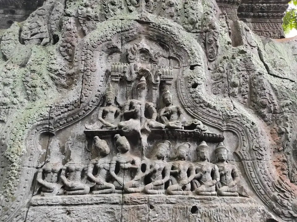 Bas-relief carving of apsaras on the outer wall of Ta Prohm Temple, featuring graceful poses and ornate headdresses