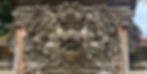Intricate stone carving of a mythical creature with floral patterns on a temple wall, featuring earthy tones, under a clear sky.