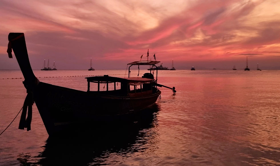 Silhouette of a boat on calm water with a vibrant pink and orange sunset. Sailboats on the horizon. Peaceful and serene ambiance.