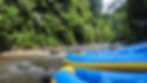 Blue and yellow rafts on a flowing river amid lush green jungle. Bright daylight enhances the vibrant colours and serene setting.