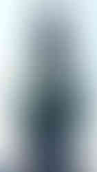 A vibrant green and blue statue of a celestial figure with elaborate crown and armor-like scales, holding a blue orb in one hand and a lotus-topped staff in the other. The figure's head is adorned with intricate flame motifs and coiled serpent