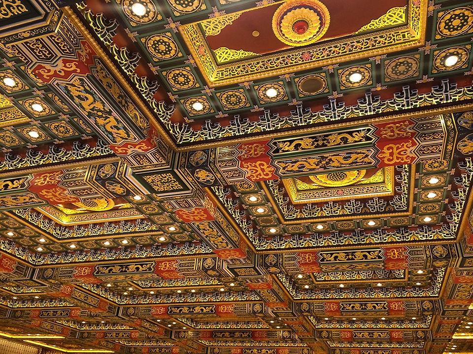 Ornate ceiling with red, gold, and black patterns, featuring intricate designs and numerous recessed lights, creating a luxurious atmosphere.