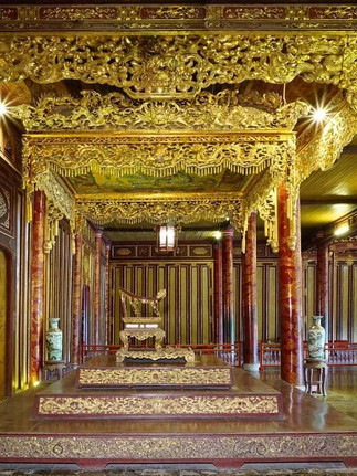 heavily ornate gold ceiling with red timber pillars looking at a gold throne on red steps