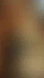 Ancient stone Buddha statue with serene expression in meditation pose, set against a backdrop of rustic red brick arches.