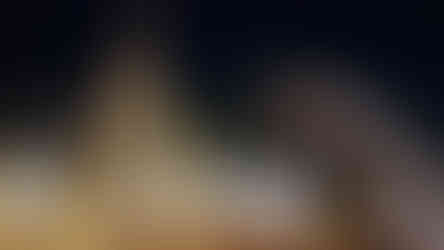 Golden spire adorns ornate temple at night, surrounded by orange flags and intricate details, set against a dark sky. Peaceful ambiance.