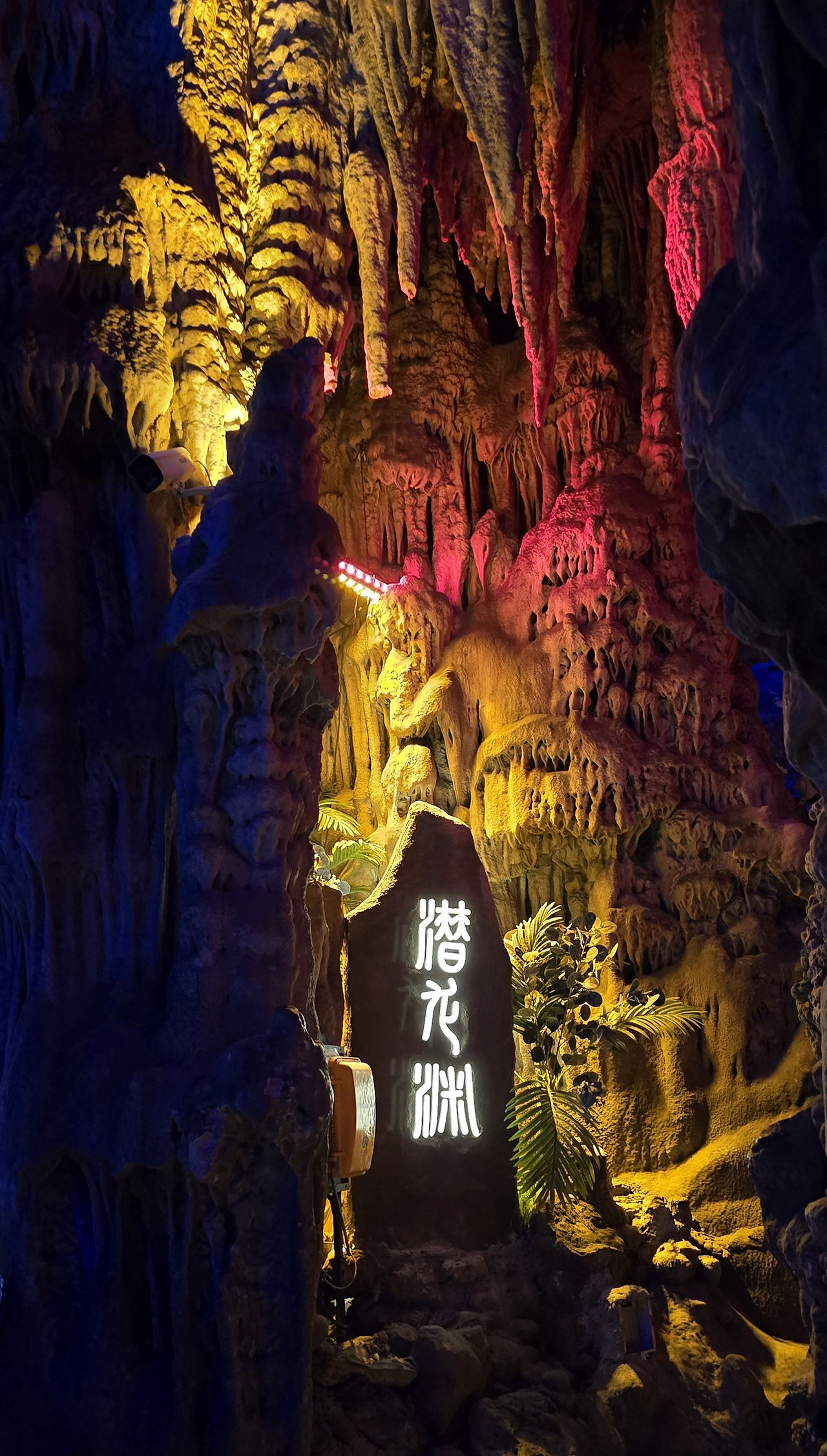 luster of stalactites and stalagmites meeting to form columns, small black timber sign with illuminated chinese writing