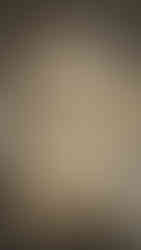 Stone sculpture depicting a goddess with flowing hair holding a staff, standing over a figure. Set against a marbled wall backdrop.