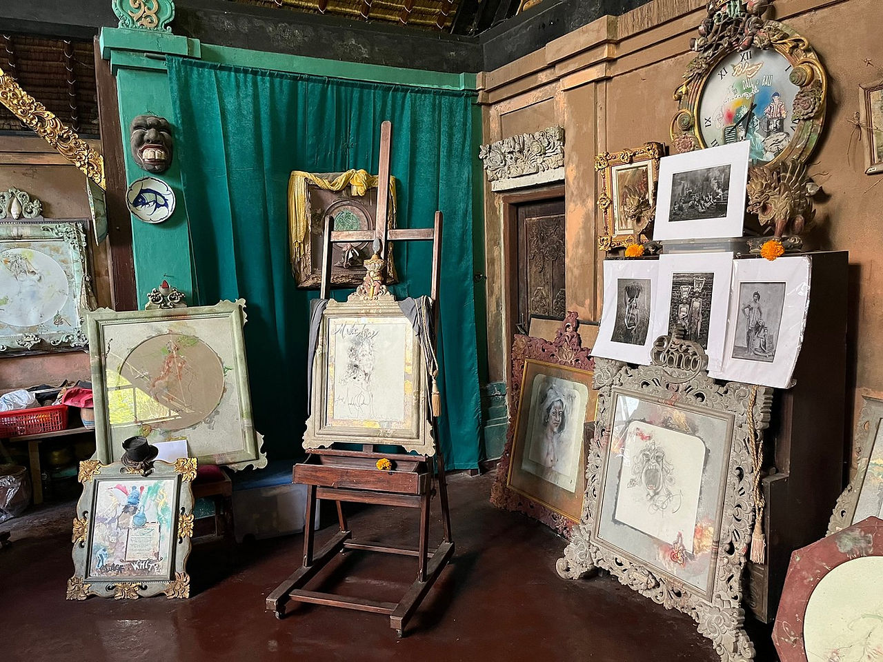 Art studio with framed sketches and paintings on easels against teal curtains. Ornate clock and art pieces create a vintage mood.