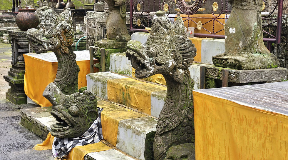 Mossy stone naga statues guard a Hindu shrine with yellow-and-white drapes and a golden swastika emblem on the gate.