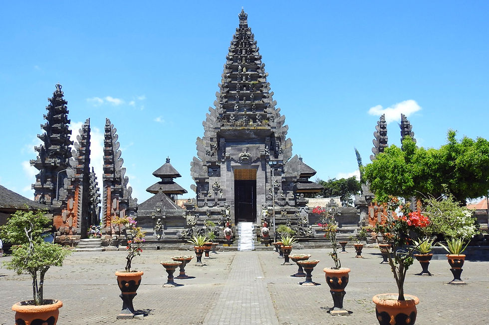 Ancient temple with tiered towers under a clear blue sky. Potted plants line a stone path, creating a serene atmosphere.