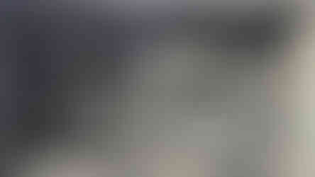 Stone relief of figures in intricate detail, featuring multiple people with headdresses in a scene, set on an ancient textured wall.