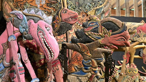 Intricately carved and colorfully painted wooden puppets in a display, featuring vibrant patterns and expressive faces in a wooden setting.