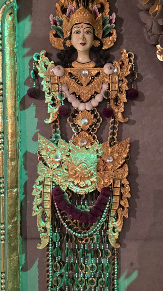 Intricate golden deity statue adorned with jewels, set against ornate, dark temple architecture featuring detailed carvings and patterns.