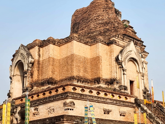 ancient brick temple, flanked by elephant carvings, under clear sky. Intricate details and historic atmosphere.