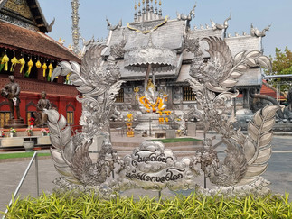 An ornate silver statue in the middle of the temple complex featuring ferns