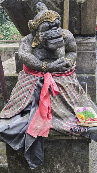 Weathered stone guardian statue in red and plaid cloth, with flower offerings and smoking incense at a temple, solemn and sacred