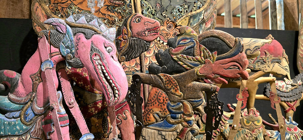 Colourful traditional puppets with intricate patterns are displayed together. The setting is bright, emphasizing the wooden textures.