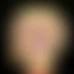 Ceremonial mask with bold red and gold details, large eyes, and tusks on a black background. Intricate sunburst patterns add drama.