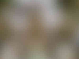 Gold and green Buddha statues surrounded by blue statues and gold floral sculptures in a serene bamboo garden setting.