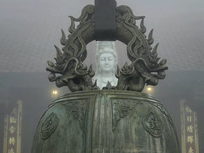 A stone Buddha statue framed by intricate dragon carvings with foggy background. Soft lighting creates a serene atmosphere.