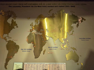 Bronze world map showing countries Ho Chi Minh visited (1911-1969). Illuminated spots mark locations. Pacific, Atlantic, Indian Oceans labeled.