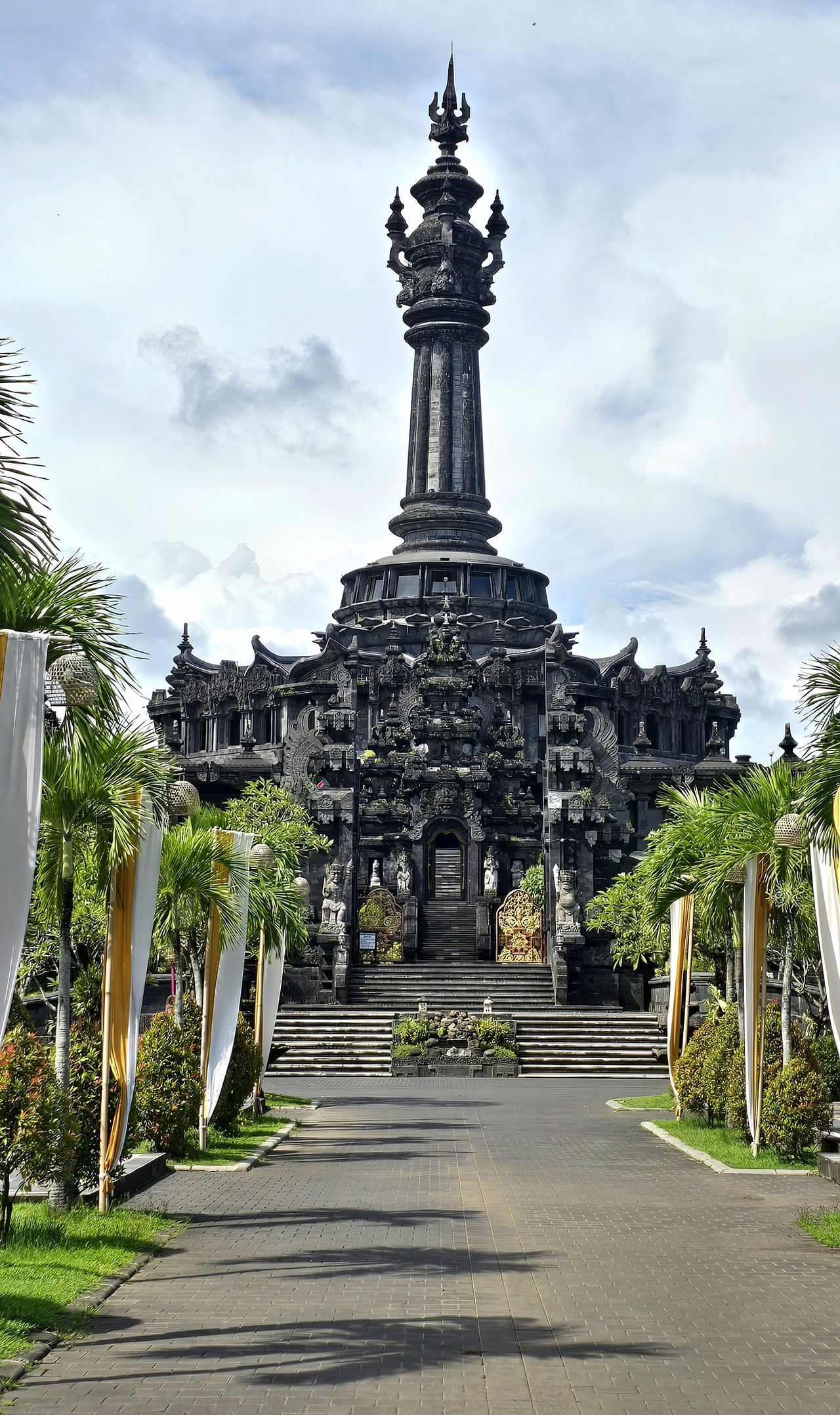 grand monument, pathway lined with verdant green trees and colourful flags