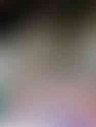 A small shrine in a cave, adorned with many rainbow coloured cloths, drink cans, phallic carvings and symbolic items left by worshippers