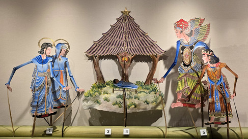 Shadow puppets depict a nativity scene with blue and colourful figures under a star topped roof. Green grass details the setting.