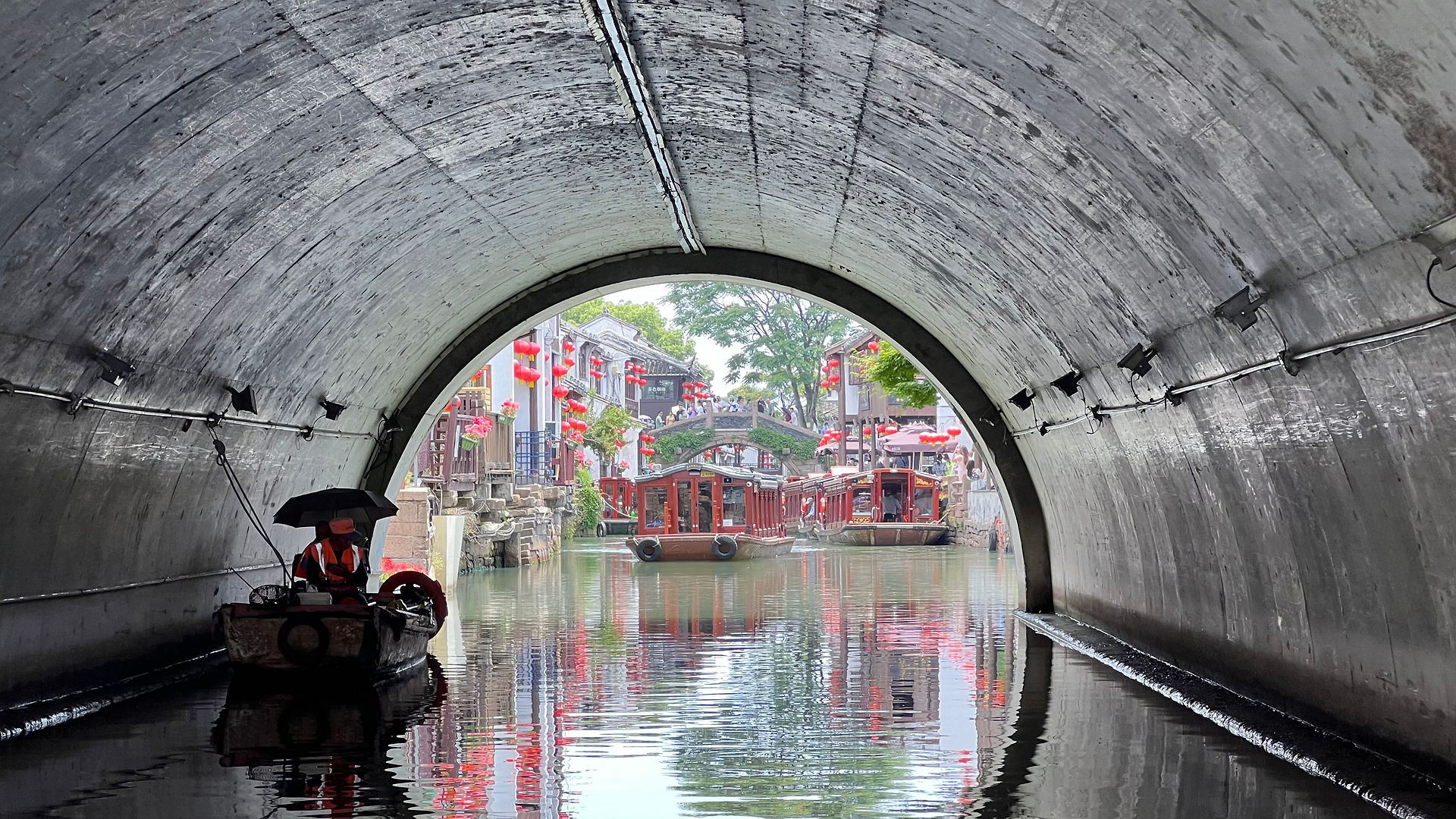 round bridge with traditional boats floating on the river, reflections