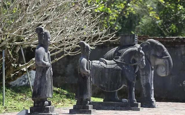 2 male stone statues alongside a ceremonial elephant and horse, representing the emperor’s strength and divine protection, standing guard at the entrance of King Minh Mạng’s tomb