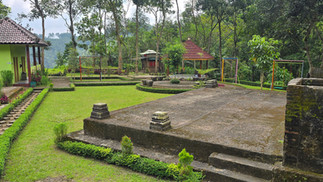 Green landscape with a small building labeled "Toilet," pagoda-style shelters, swings, lush trees, and well-trimmed grass, creating a serene atmosphere.