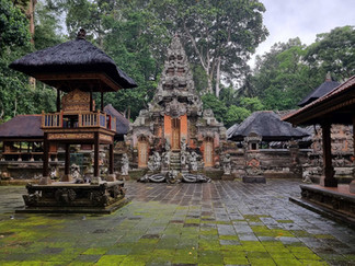 Ancient temple courtyard with moss-covered stone tiles, ornate carvings, and lush greenery. Overcast sky enhances a serene mood.