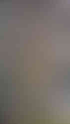 Stone statue of a mythological figure holding a club on an aged, mossy stone background. Bright flower offerings at its base.