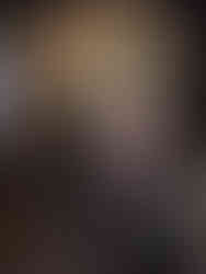 A menacing ogre mask with sharp teeth and wild hair is on display, set against a dark background with colourful patterned fabrics.