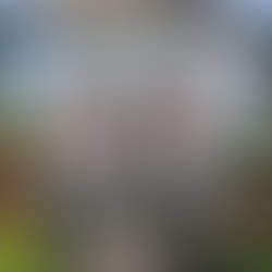 White pavilion with intricate carvings and red parasol-topped statues. Surrounded by water and greenery, creating a serene ambiance.