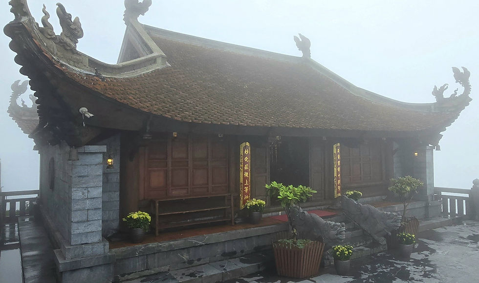 Misty temple with ornate roof, dragon carvings, and potted plants. Wooden doors display yellow text. Overcast ambiance.