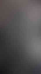 Ancient stone sculpture of a deity stands in an ornate pose on an animal, in a dimly lit historic setting. Intricate carvings adorn the figure.