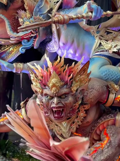 A fierce mythical creature with flaming hair and ornate gold armor, roars amidst vivid colours and elaborate decorative details.