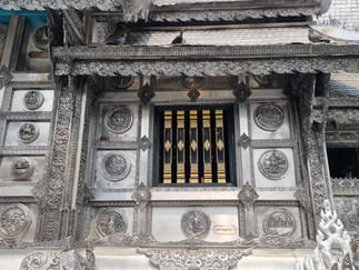 Side view of the intricate temple walls, 5 gold bars covering the windows