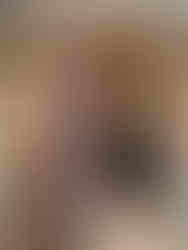 Two traditional Balinese performers in ornate, colorful costumes stand in a decorated temple setting, performing a ritual dance.