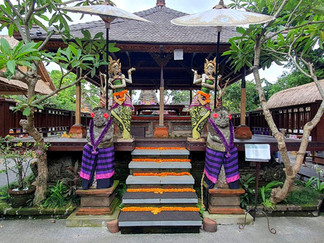 entry gate, 2 ornate statues wearing pink and purple sarongs, orange flowers up the central steps