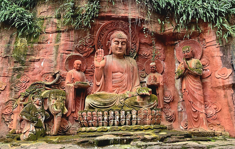Moss-covered reliefs etched into a red rock face, with intricate Buddhist imagery 