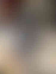 Colorful dragon sculpture with intricate patterns on steps outside a building with red shutters. Playful and vibrant atmosphere.