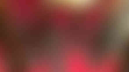 Display of ornate daggers in a glass case on a red background. Each dagger has a decorative hilt and is placed on an intricate stand.