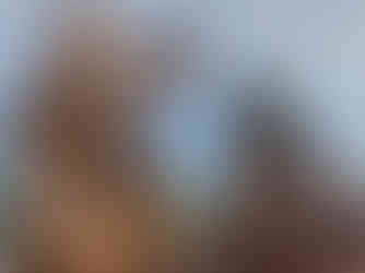 Bronze statues of figures offering objects, with trees in the background under a partly cloudy sky. Calm, serene mood.