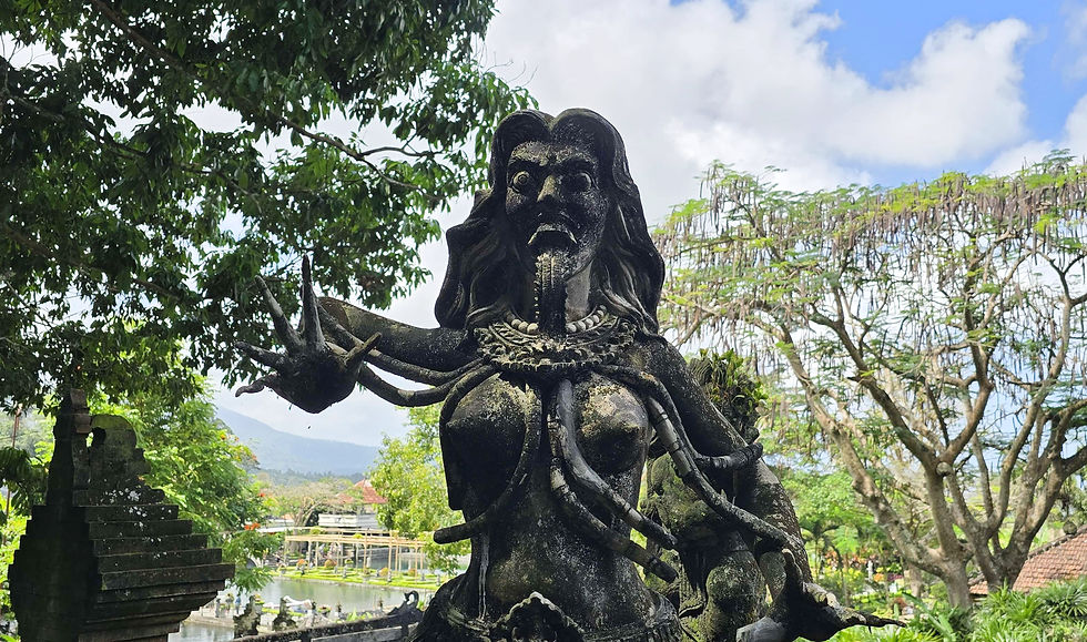 Stone statue with tentacles and fierce expression in a lush garden setting, surrounded by trees under a partly cloudy blue sky.