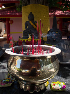 Incense smoke swirls around the Buddha statues and golden pots at the Vihara Dharmayana Pagoda in Bali, creating a tranquil spiritual ambiance