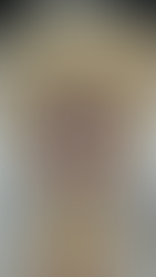 Ornate Balinese mask with big red eyes, gold accents, and white teeth on a black background. Feathers and checkered fabric surround it.